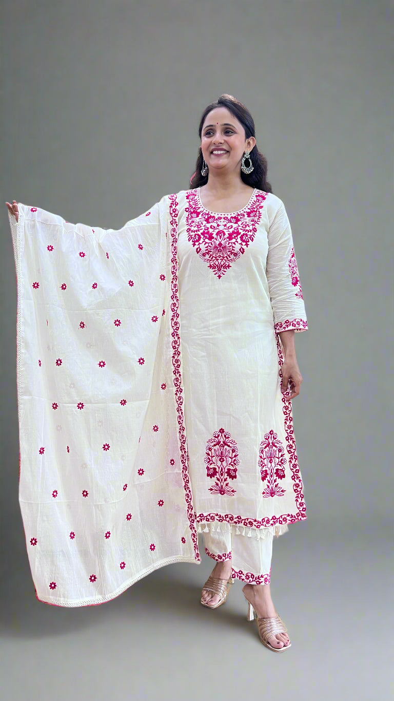 Woman wearing a white and pink embroidered traditional outfit in a store setting.